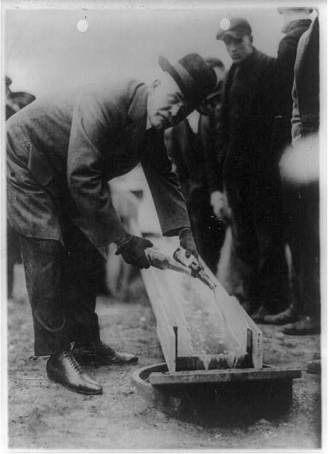 Man dumping beer into the sewer during the Prohibition